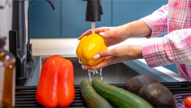 woman-washes-yellow-pepper-faucet-kitchen-clean-vegetables